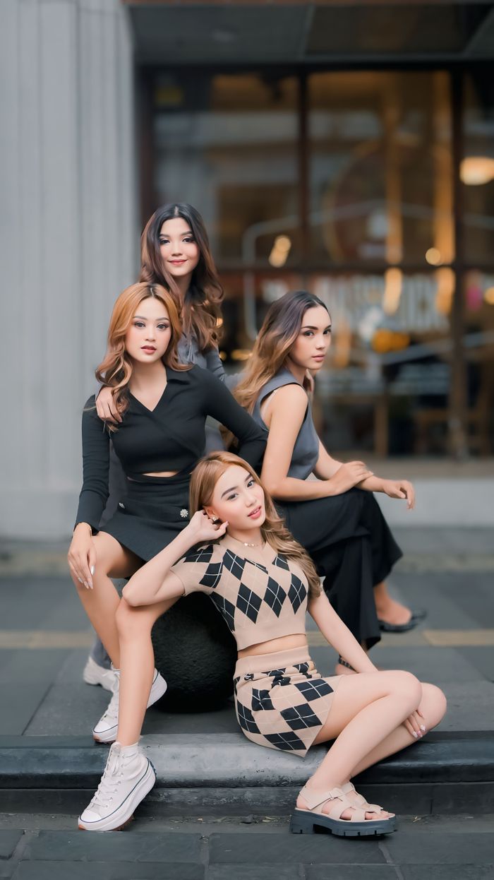 Services Four fashionable young women pose confidently outdoors in an urban environment.