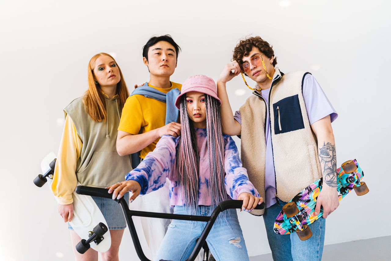 Contact Four stylish friends posing with skateboards and a bicycle, showcasing modern fashion.