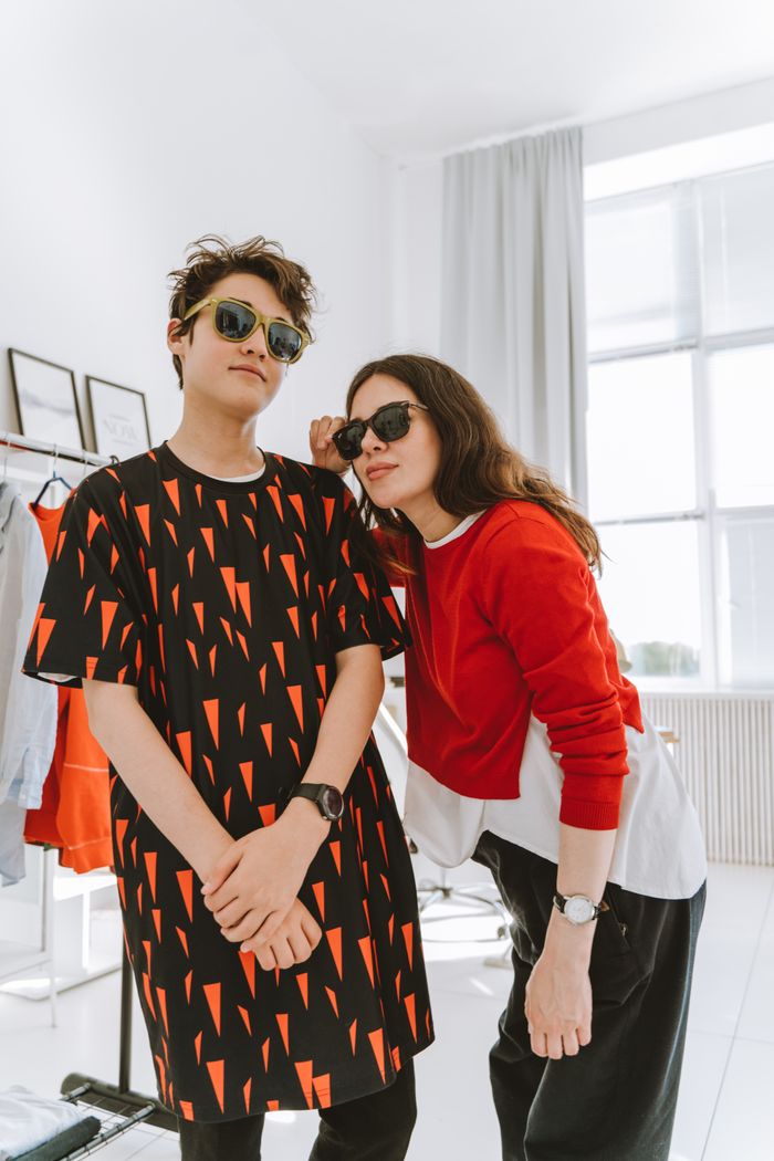 Services A fashionable duo, mom and teen, posing stylishly indoors, both wearing sunglasses.