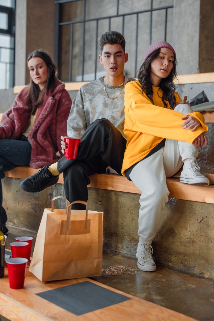 Services A group of stylish young friends sitting indoors, enjoying casual drinks and conversations.